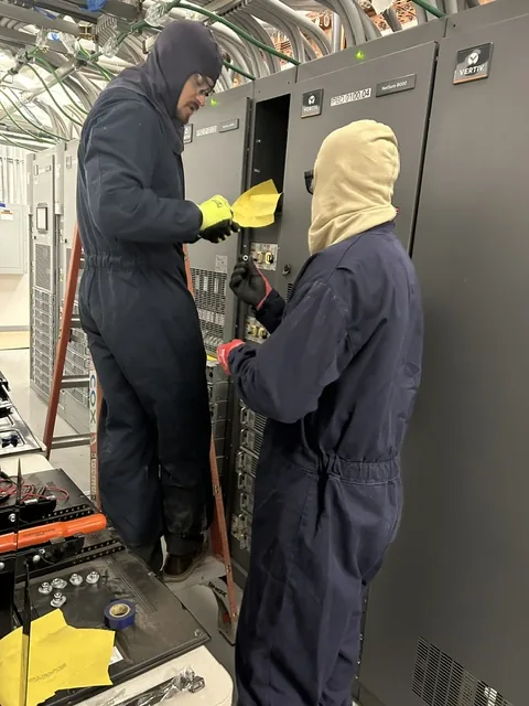 New Phase technicians in arc-flash PPE performing energized work on switchgear inside an Arizona data center