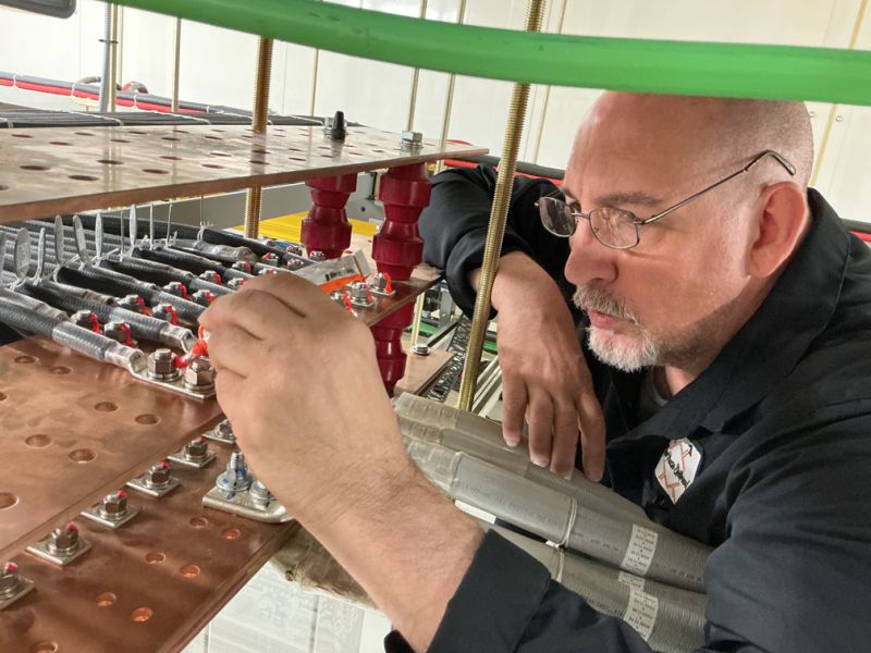 New Phase technician working on battery bus connections at Arizona critical facility